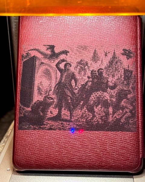Detailed artwork engraved into a burgundy Kindle case